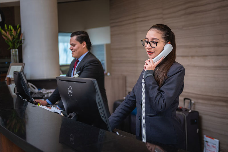 Hotel receptionists assisting international guests at check-in desk
