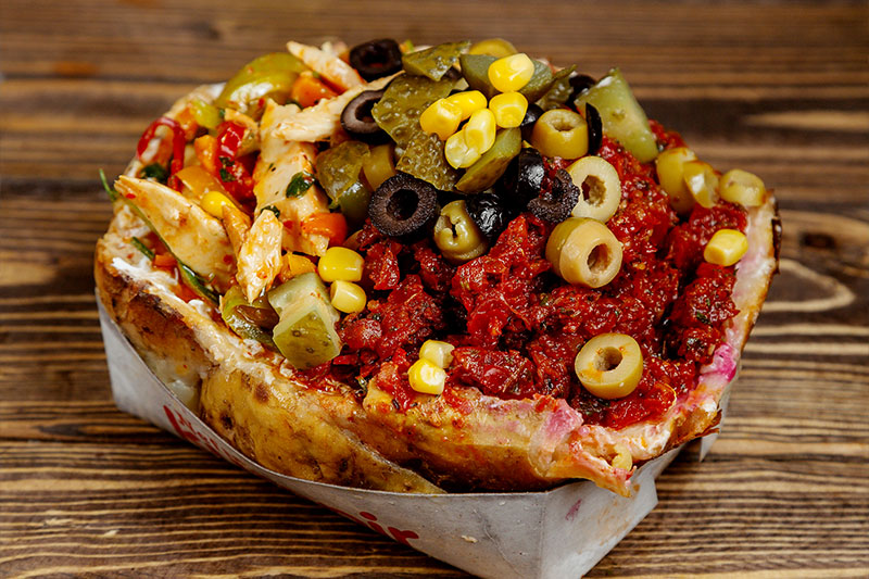 Baked potato stuffed with colorful toppings like olives and sausage