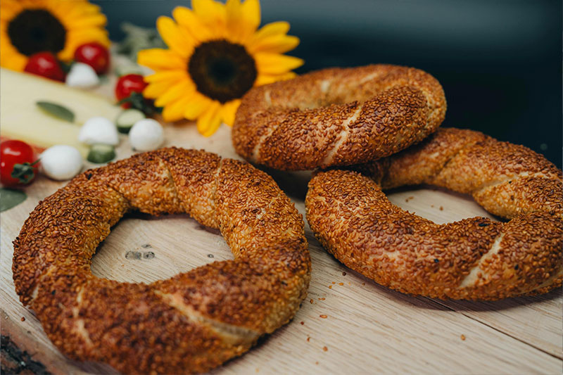 Fresh sesame-covered simit stacked on a wooden tray