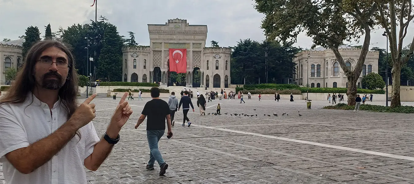 Ali in front of Istanbul University gate at Beyazıt Square, giving a travel explanation