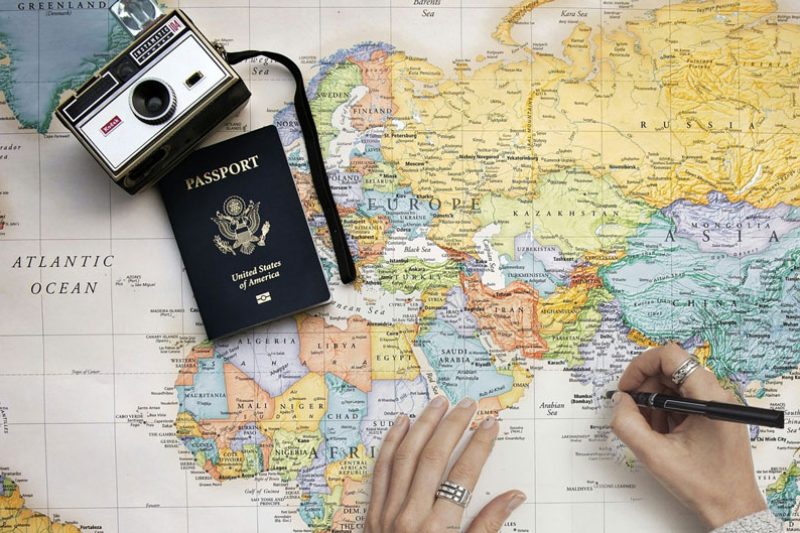 Tourist marking a map beside a camera and passport